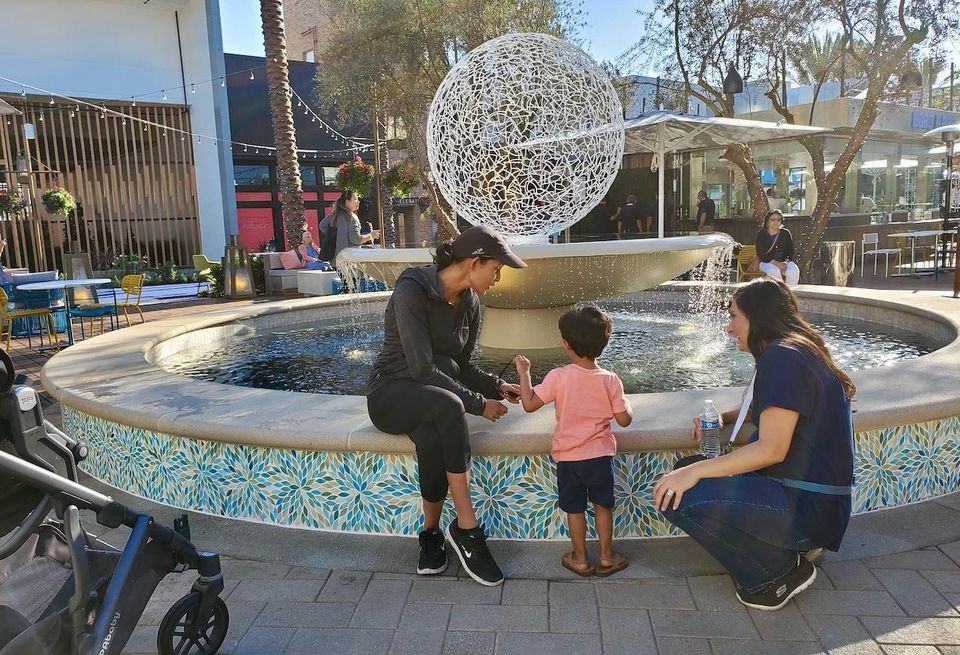 A young boy plays in front of an outdoor water fountain at the opening of CenterCal Properties' 2nd & PCH shopping center in Long Beach