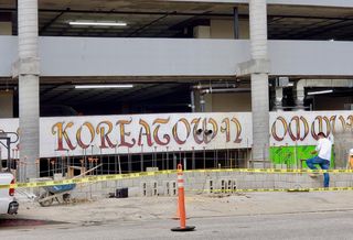 A construction worker stands next to a construction site soon to be an eight-story, 61-unit apartment at 689 S. Catalina St. in the Koreatown neighborhood of Los Angeles