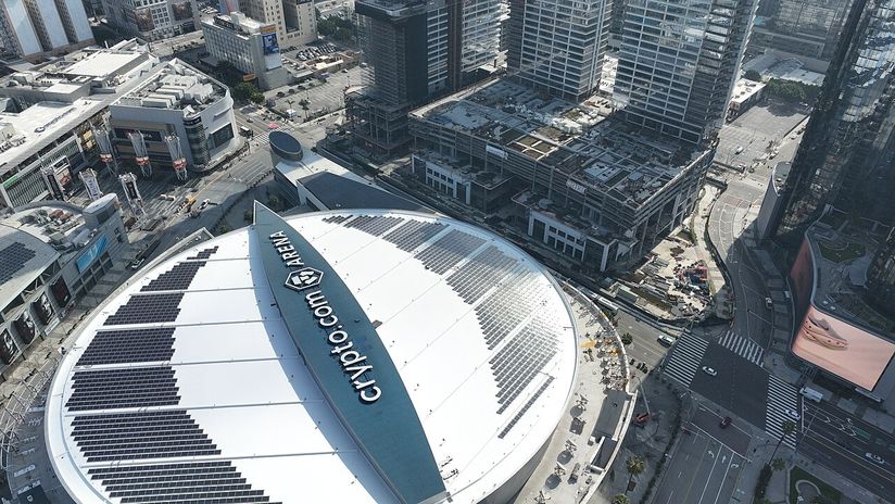 Aerial view of the Crypto.com Arena roof with solar panels, surrounded by urban buildings and roads in Downtown LA.