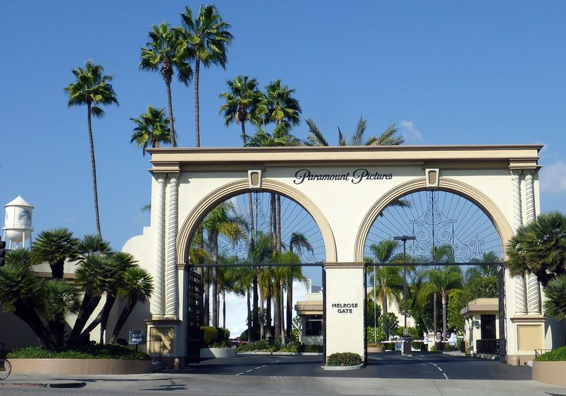 Entrance of Paramount Pictures studio with arched gates, palm trees, and blue sky.