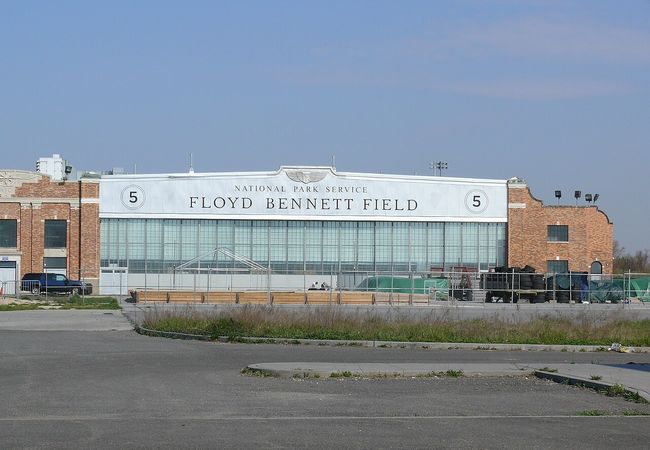 The exterior of Floyd Bennett Field, a historic aviation building with brick walls and large windows, under a clear blue sky.