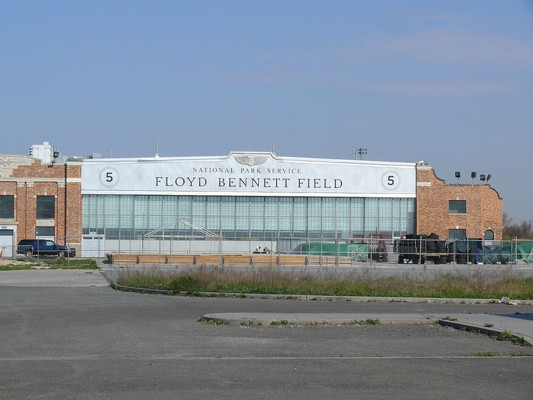 The exterior of Floyd Bennett Field, a historic aviation building with brick walls and large windows, under a clear blue sky.