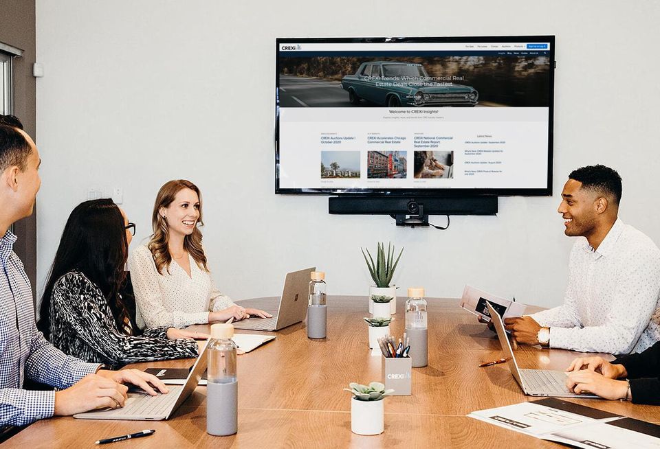 Five employees at a real estate startup meeting in a conference room.