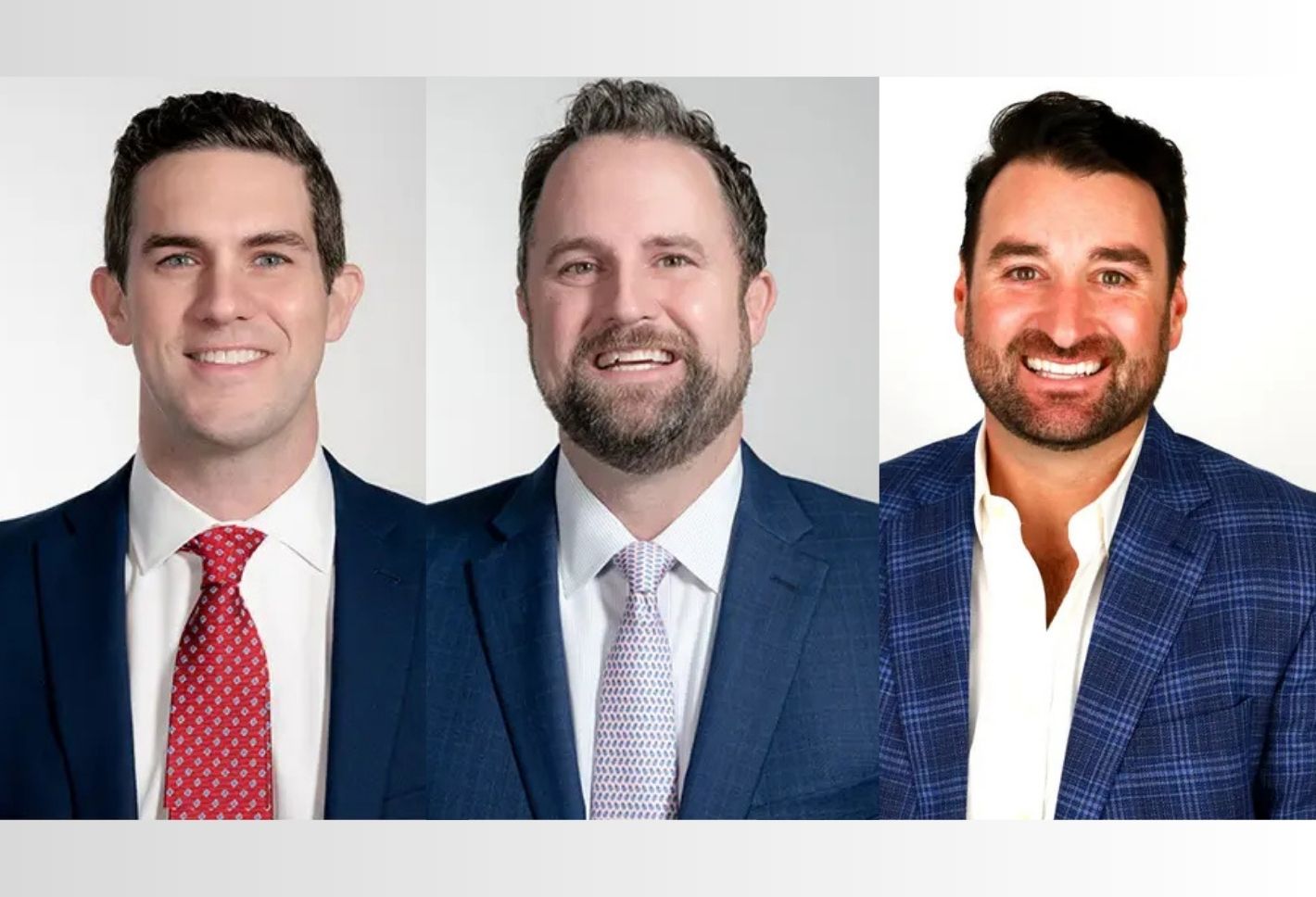 Three men in suits smiling at the camera against a plain white background.