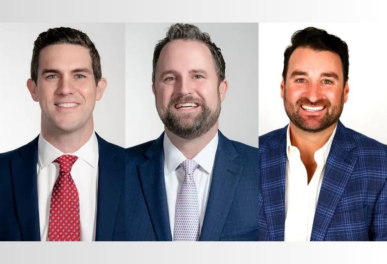 Three men in suits smiling at the camera against a plain white background.