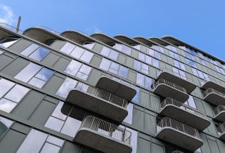 Modern building with staggered balconies and large windows under a clear blue sky.