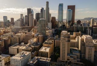 Aerial view of the Los Angeles skyline with skyscrapers under a clear blue sky.