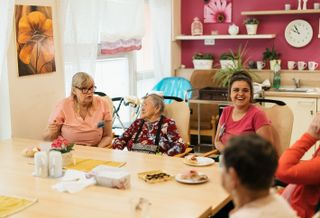 Seniors and caregivers sit around a table.