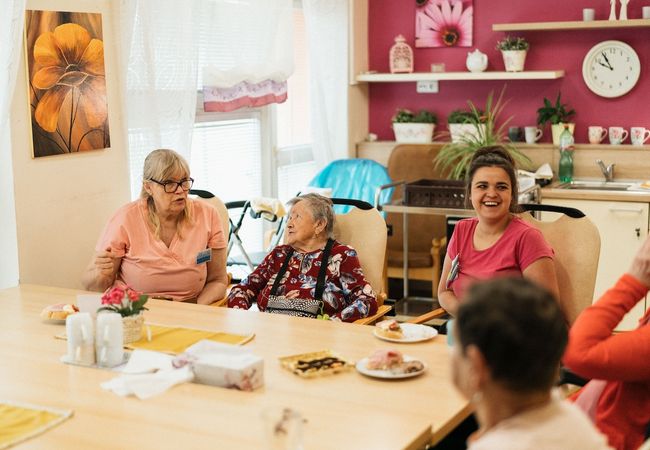 Seniors and caregivers sit around a table.