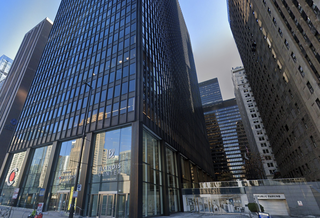 Tall glass and steel high-rise building in a city, with reflections, labeled "Illinois Center" at the entrance.