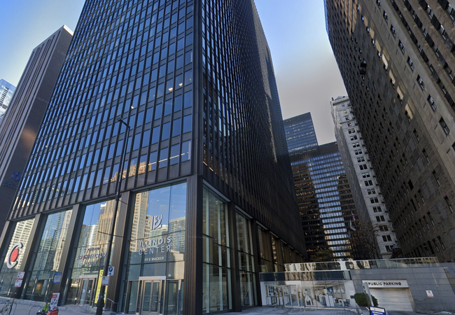 Tall glass and steel high-rise building in a city, with reflections, labeled "Illinois Center" at the entrance.