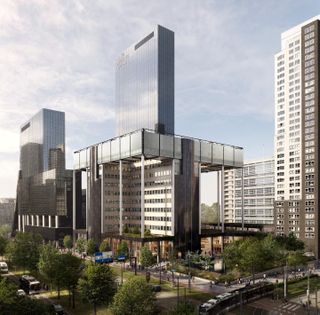 Modern cityscape with several tall glass and steel skyscrapers, surrounded by lush greenery, roads, and a tram in the foreground.
