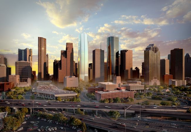 A city skyline at sunset featuring tall skyscrapers, highways with traffic, and scattered clouds in the sky.