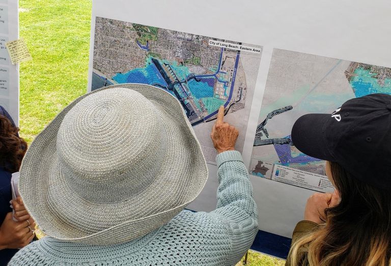A woman points at an area in the Naples neighborhood of Long Beach that could possibly be affected by sea level rise due to climate change during a climate fest in Long Beach. 