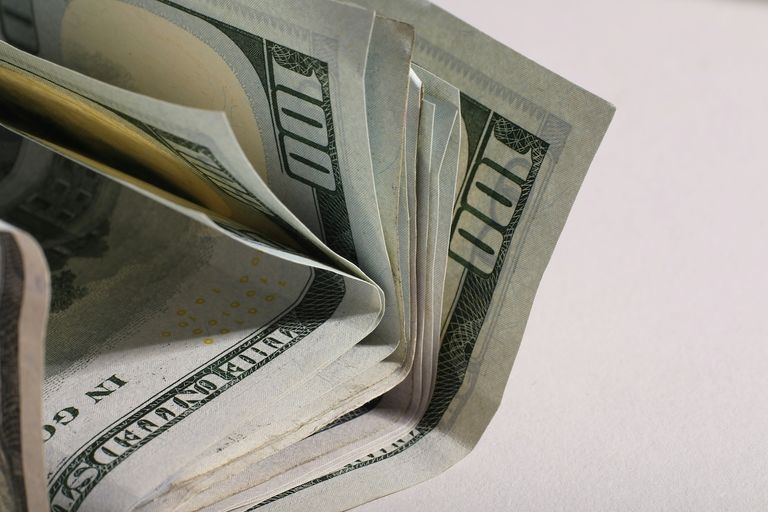 A stack of U.S. hundred-dollar bills fanned out on a light background.