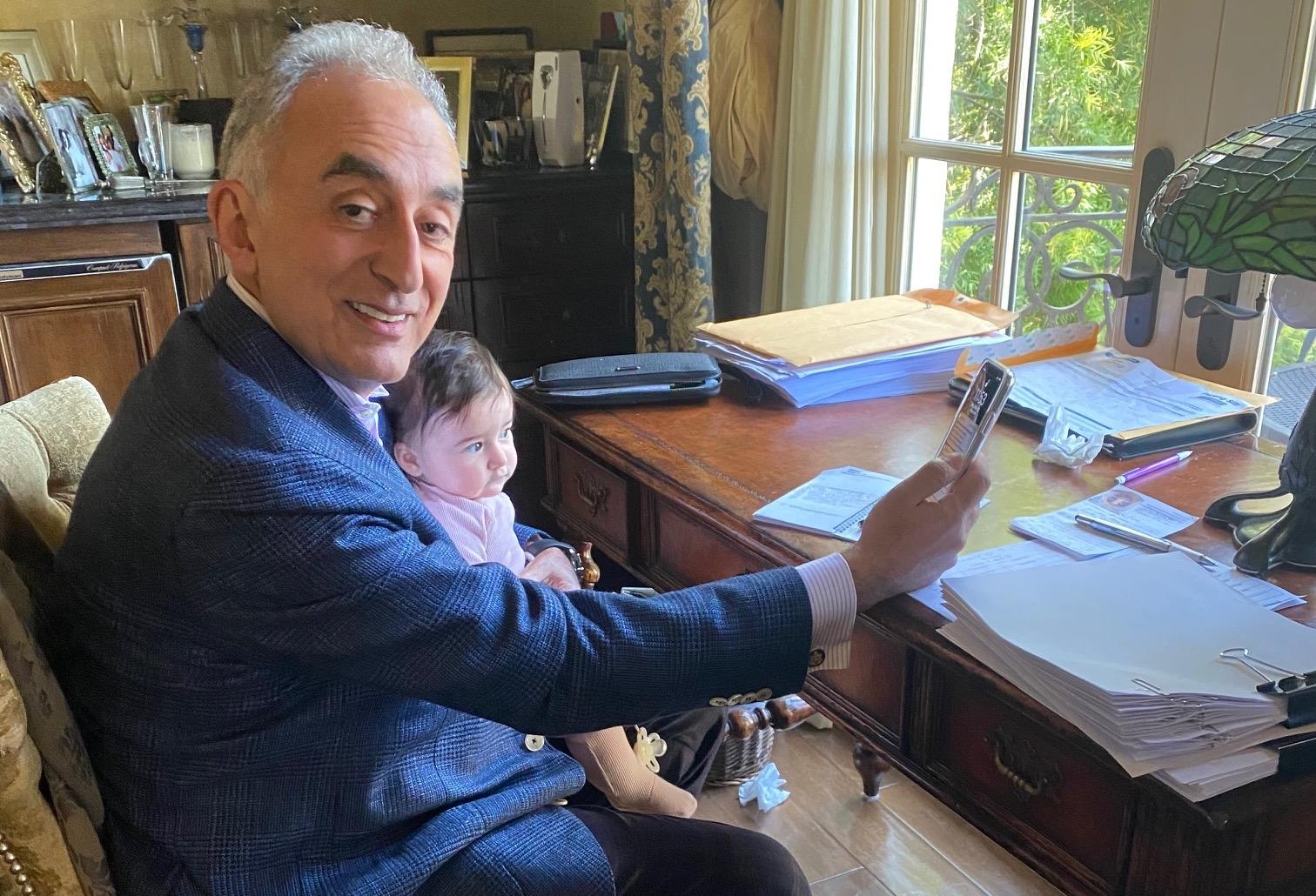Universe Holdings Chairman and CEO Henry Manoucheri holds his grandson while working from home