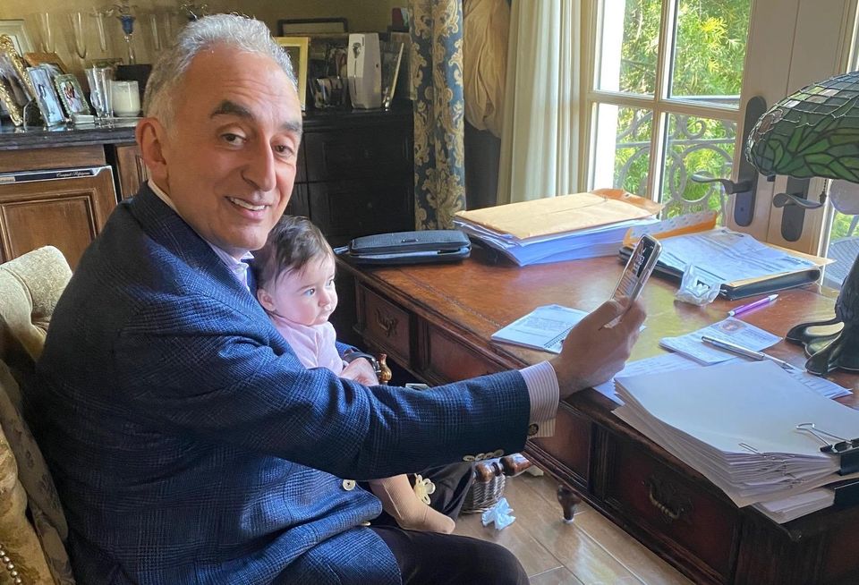 Universe Holdings Chairman and CEO Henry Manoucheri holds his grandson while working from home