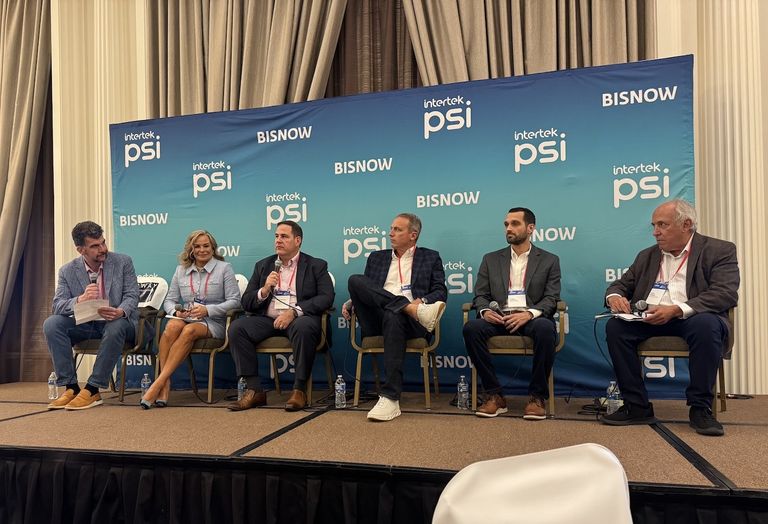 Five panelists sit onstage with microphones at a conference, with a blue backdrop displaying "intertek psi" and "BISNOW" logos.