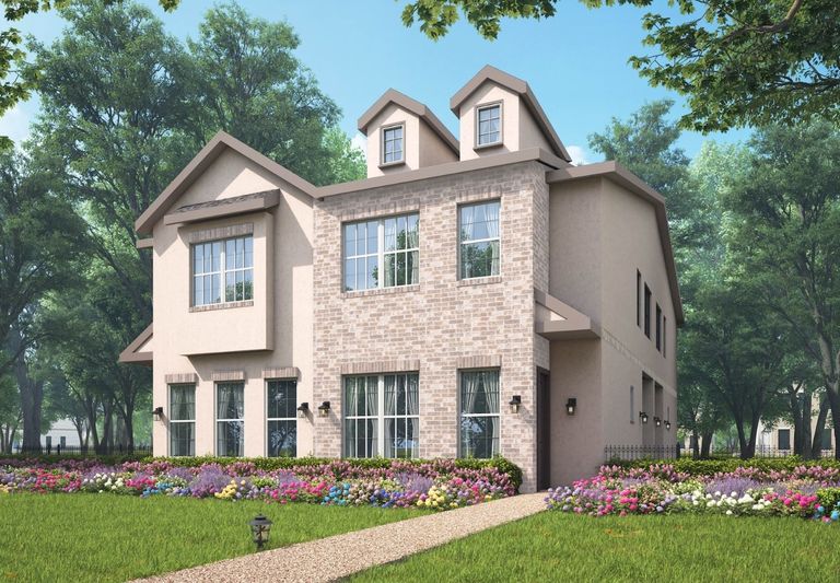 A modern two-story cottage with brick and stucco facade, surrounded by colorful flower beds and lush green trees under a clear blue sky.