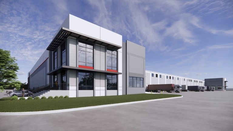 Modern warehouse exterior with large windows, loading docks, and parked trucks under a clear sky.