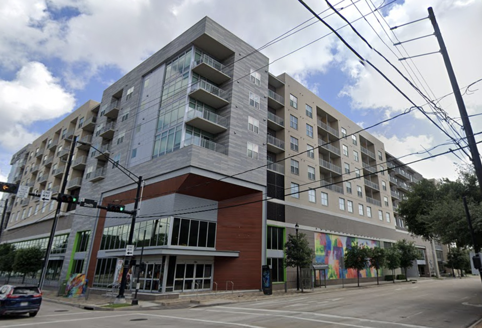 A multistory apartment complex with vacant retail on the ground floor in a dense city environment.