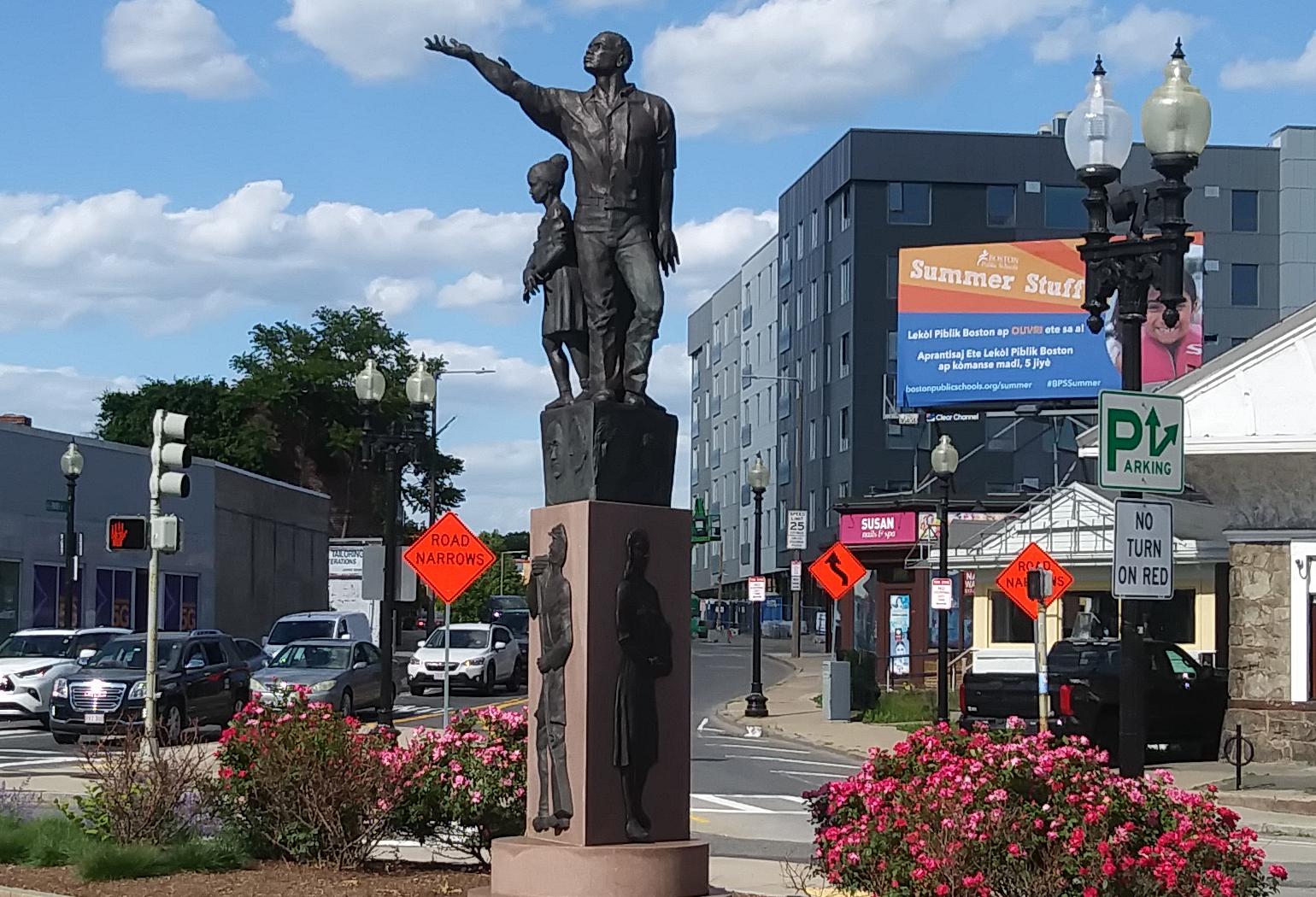 The Rise sculpture in Mattapan Square with The Loop at Mattapan Station (right) in the background.