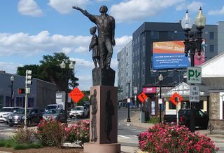 The Rise sculpture in Mattapan Square with The Loop at Mattapan Station (right) in the background.