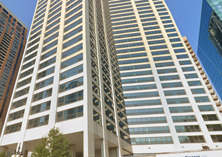 Tall modern high-rise buildingsset against a clear blue sky, with a massage and facial spa on the ground floor.