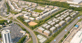 Aerial view of a suburban residential area with rows of apartment buildings, surrounding roads, a baseball field, and a nearby highway.