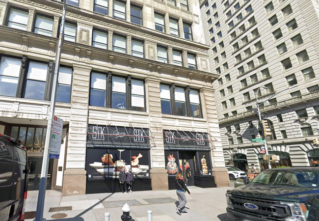 Street view of a multi-story building with STK restaurant signage on the ground floor, people walking, and vehicles parked nearby.