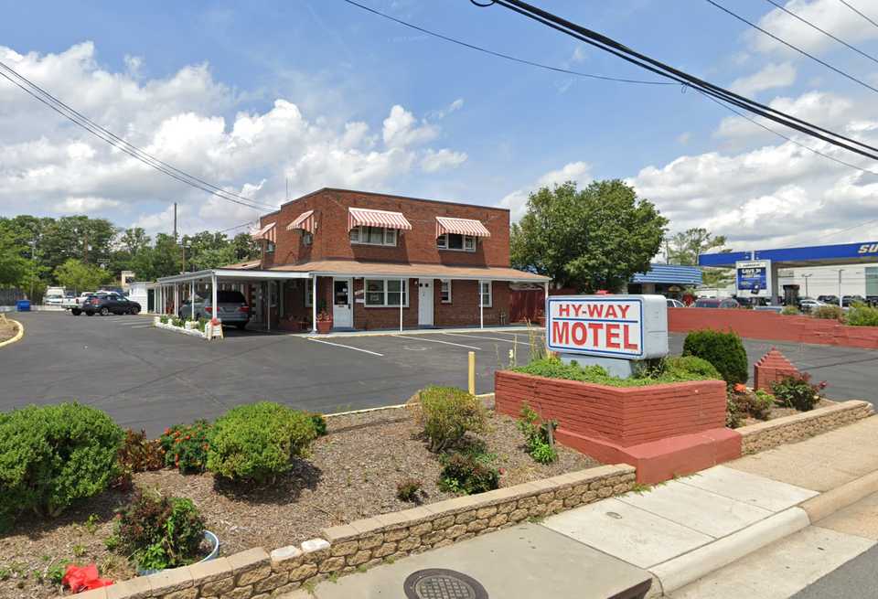 A low-slung motel with parking lot and sign saying
