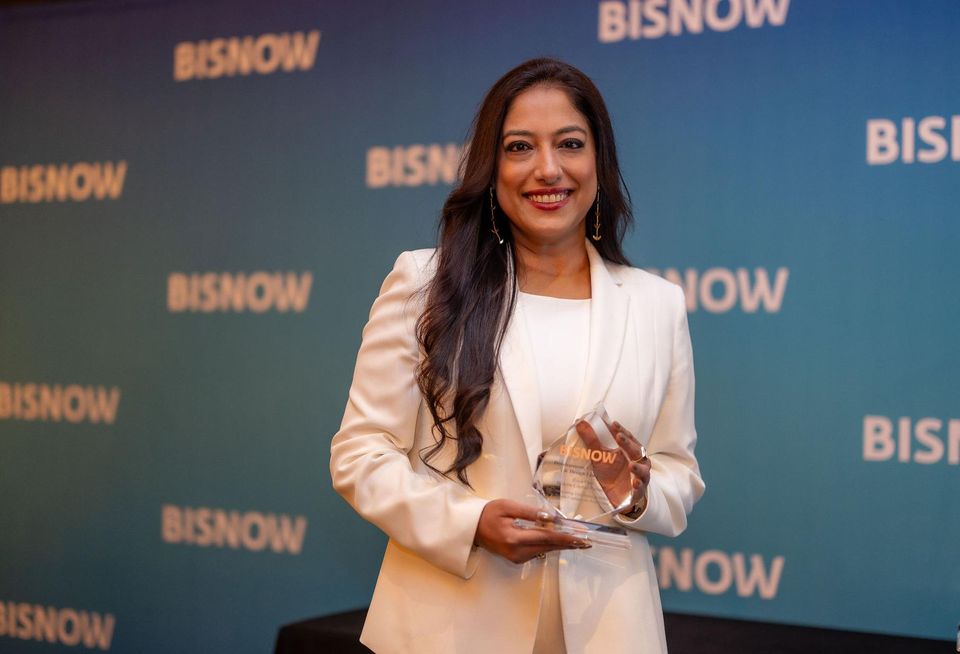 A woman holding a Bisnow award