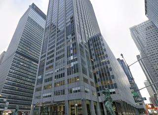 Tall modern office buildings in an urban area, with glass facades and surrounding street signs and statues.