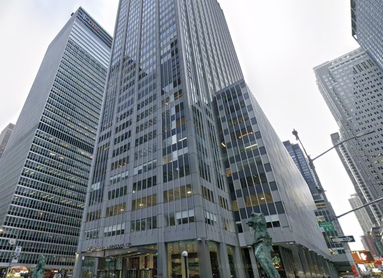 Tall modern office buildings in an urban area, with glass facades and surrounding street signs and statues.