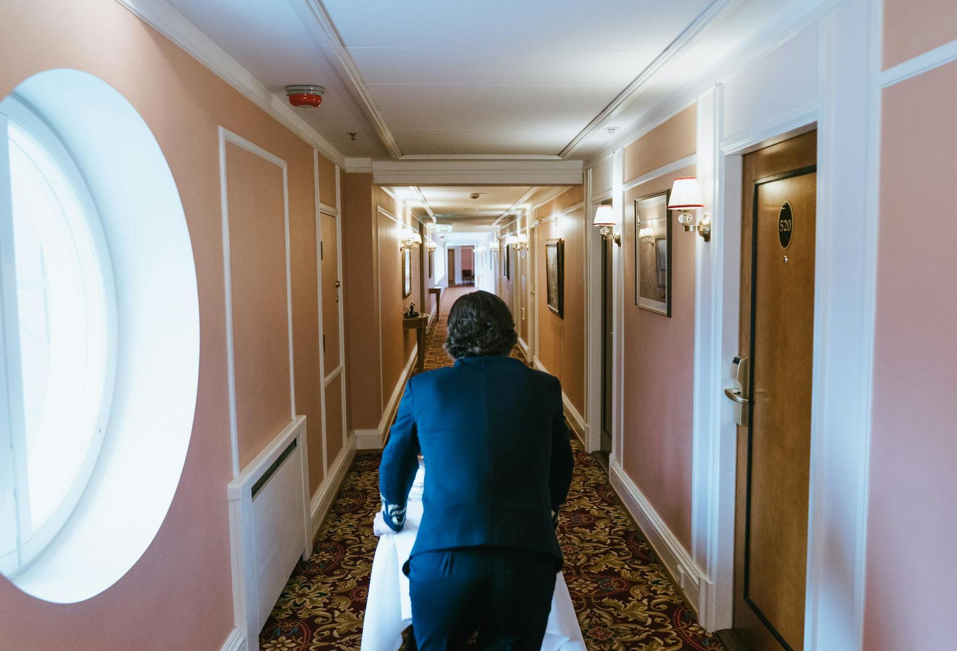 A bellhop delivering room service in the hallway of a hotel