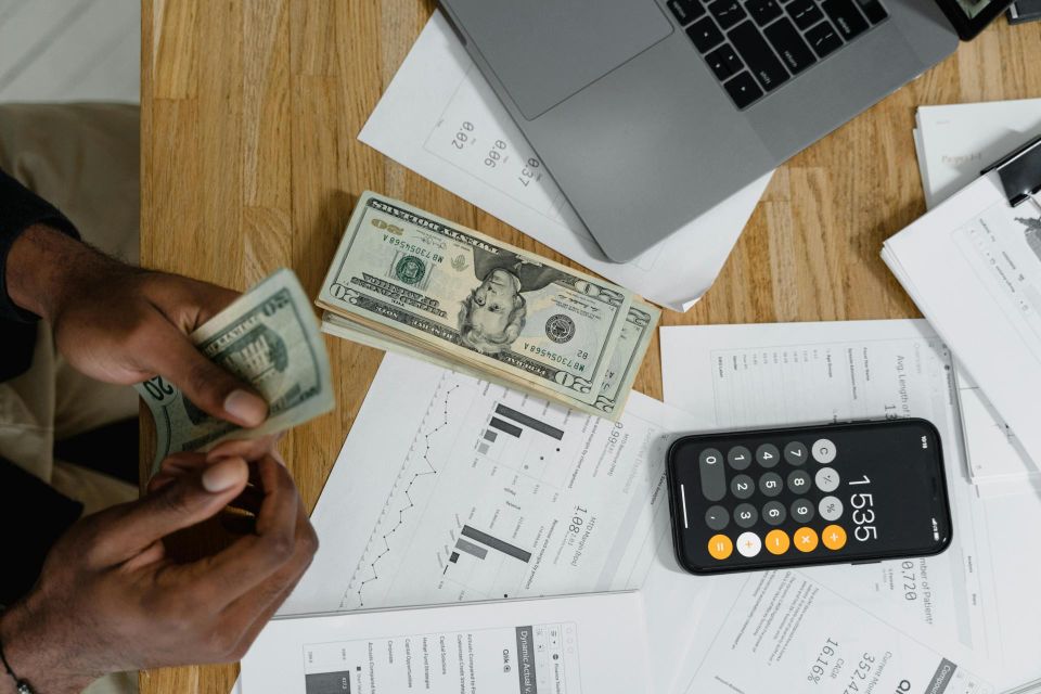 Person counting cash while using a calculator phone app.