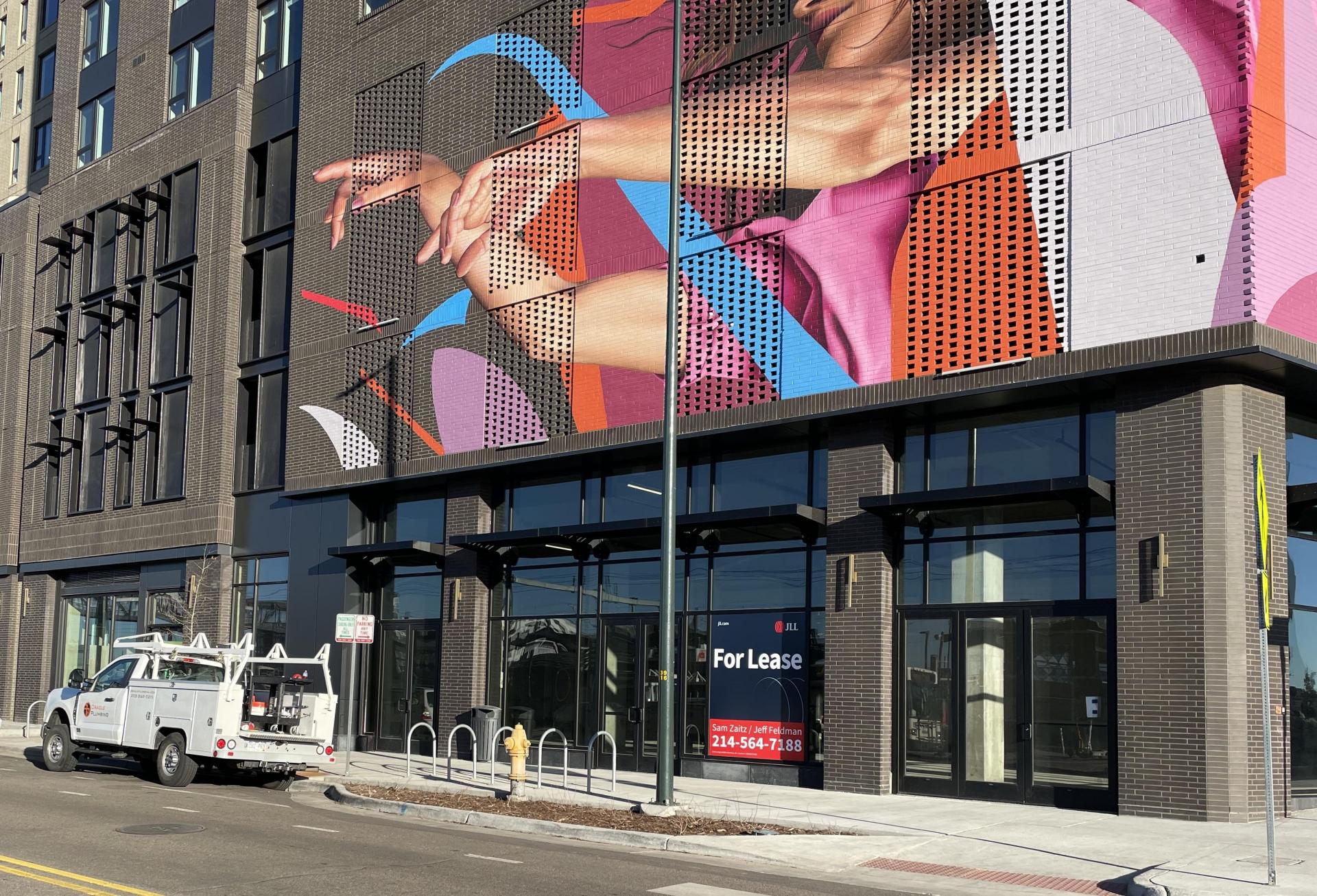 A photo of FoundryLine apartments at 37th and Blake, including a brightly colored mural above vacant retail space.