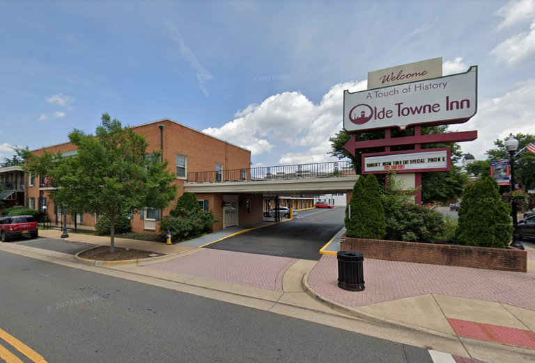 Welcome sign for Olde Towne Inn and two-story brick building with driveway