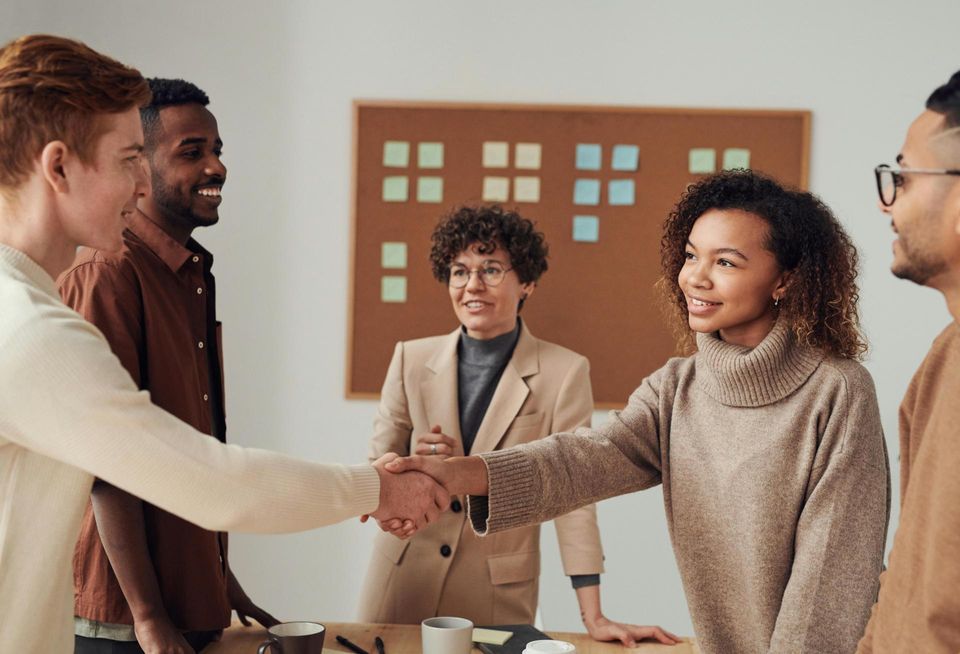 A group of people shaking hands in an office setting.