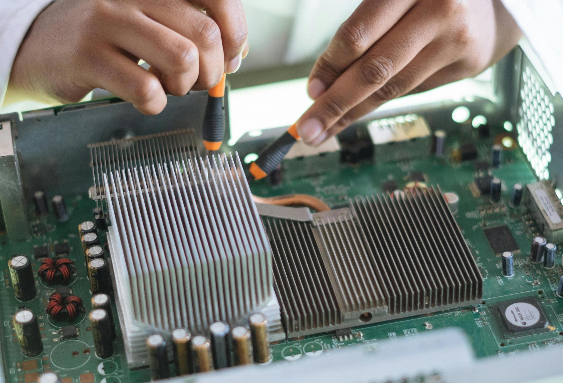 Crop technician checking contacts on motherboard in workshop

