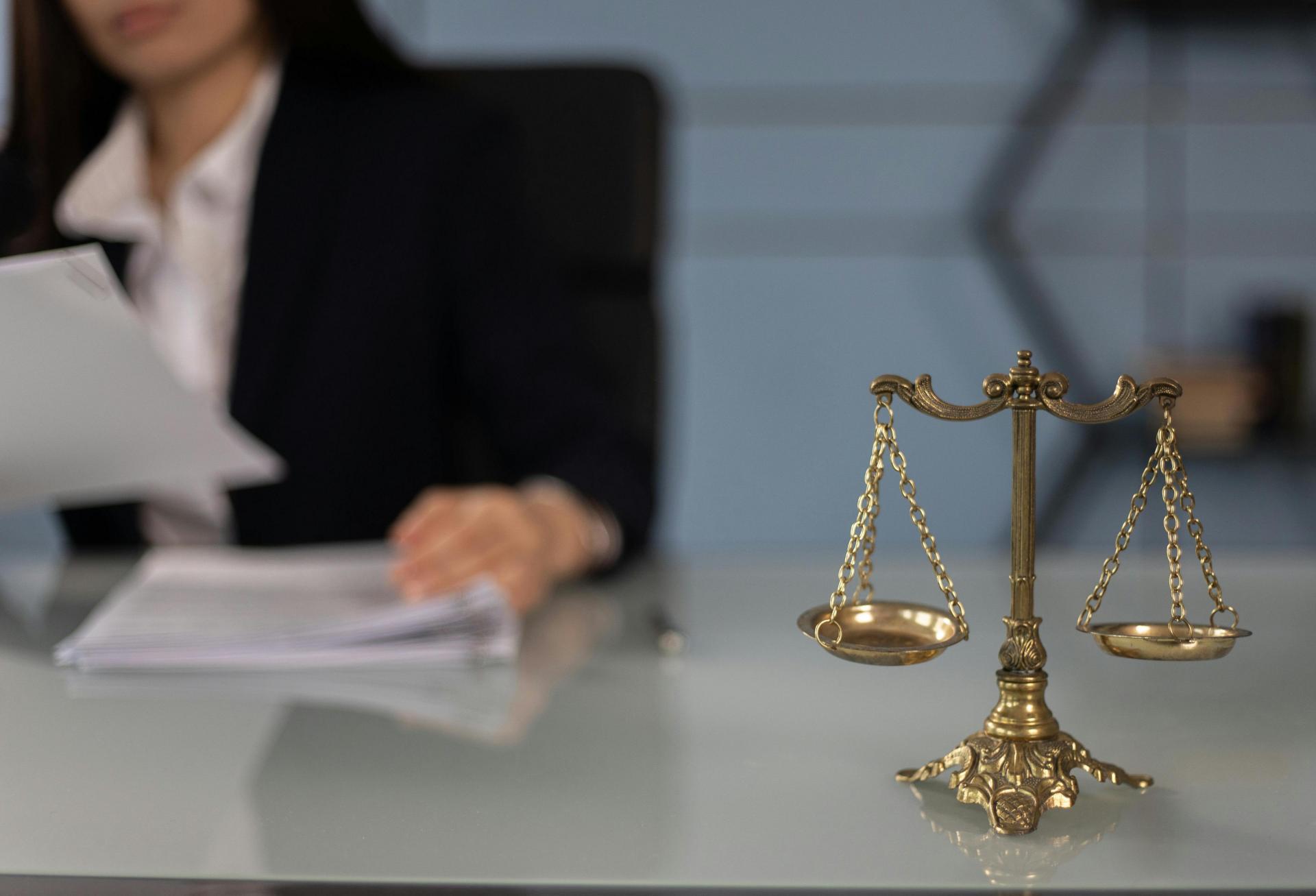 A woman sitting near the scales of justice. 