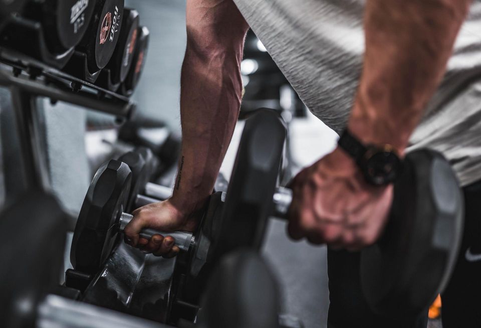 Man at gym lifting dumbbells.