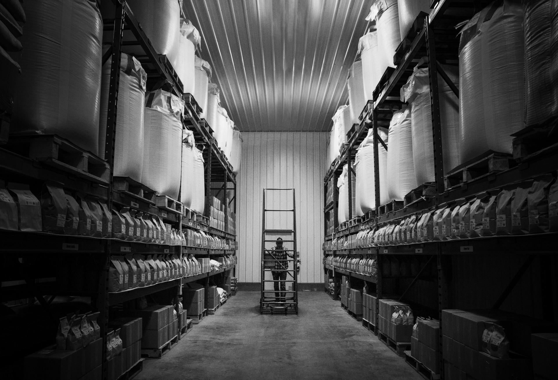 A worker pushing a metal frame in a warehouse.