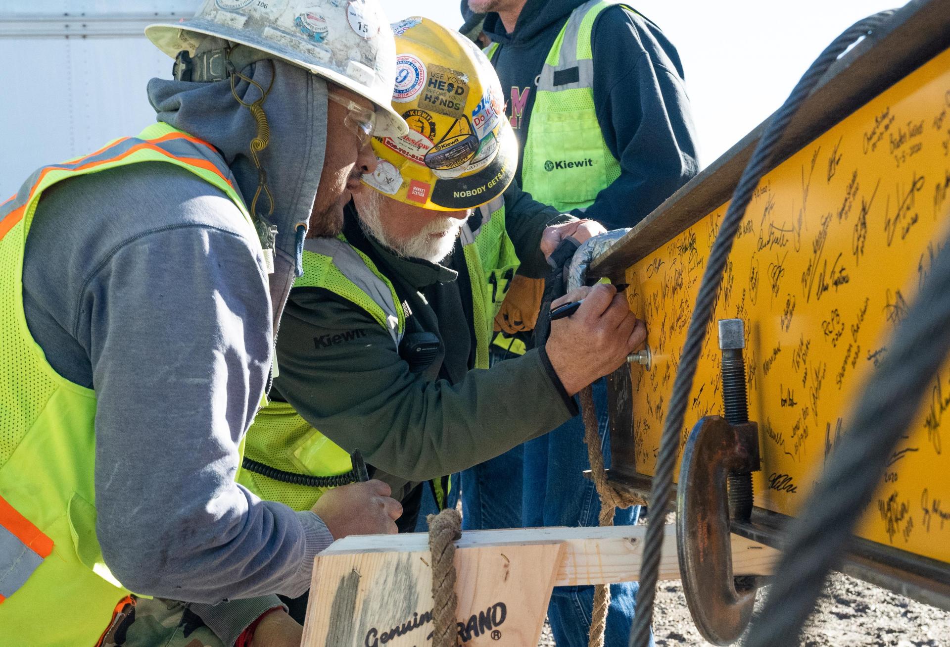 Kiewit employees add their signature to the final beam. 