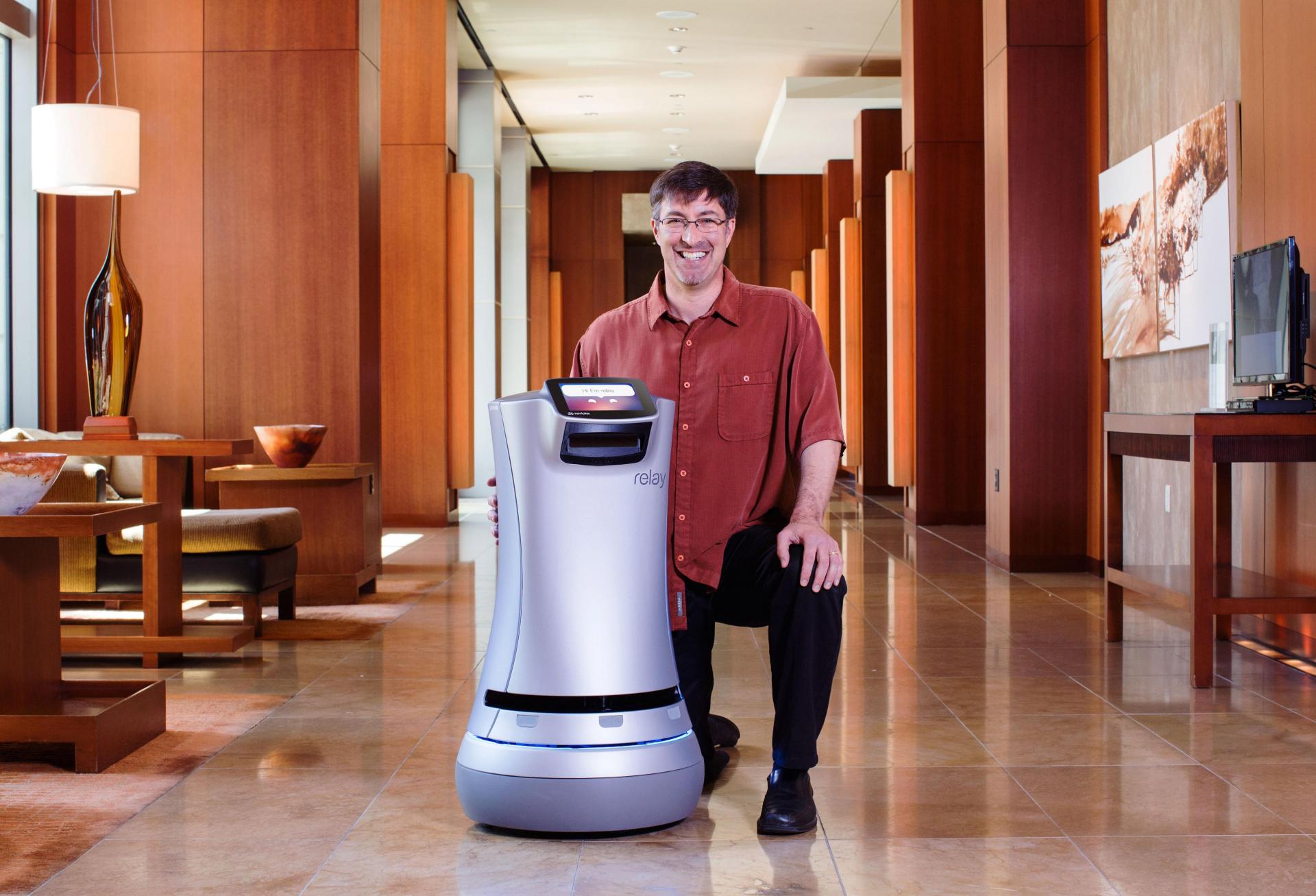 Savioke CEO founder and CEO Steve Cousins poses next to a Relay delivery robot