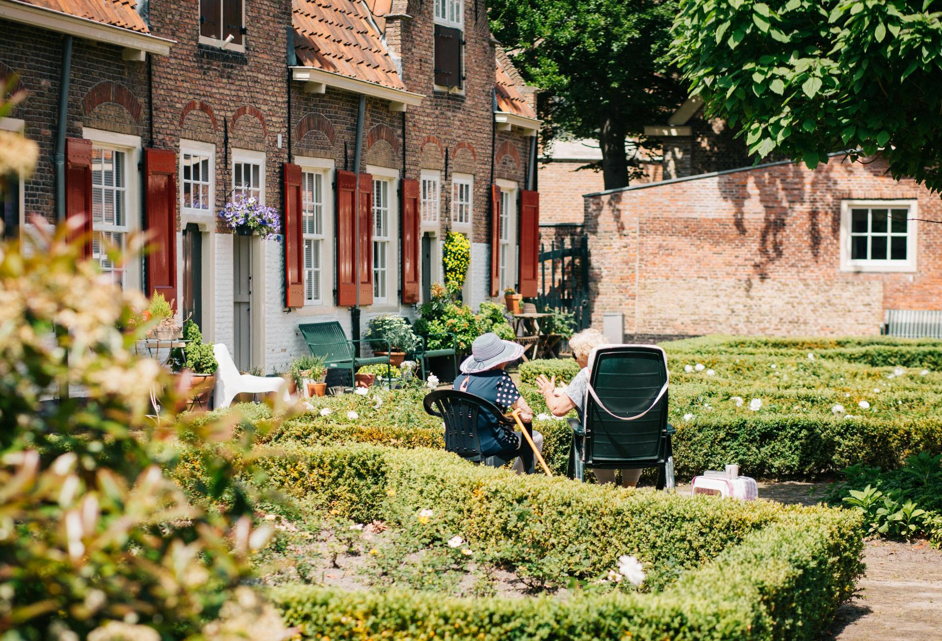 Seniors sitting in a garden outside senior living facility