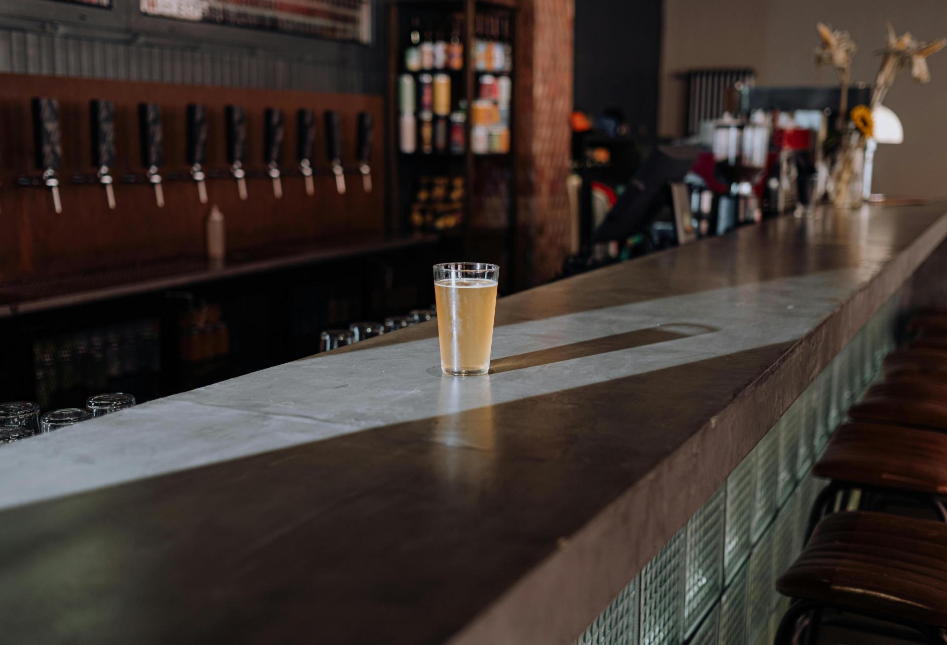 Single beer pint glass sitting on empty bar