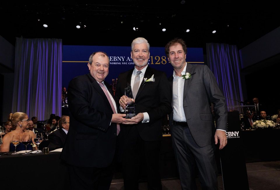 REBNY's Jim Whelan presenting Grand Central Partnership's Fred Cerullo with the John E. Zuccotti Public Service Award onstage at the trade group's 128th annual gala, alongside REBNY's incoming president Jed Walentas.