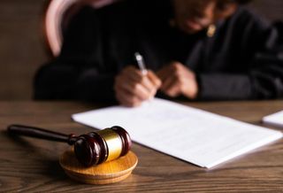 Judge writing behind a gavel. 
