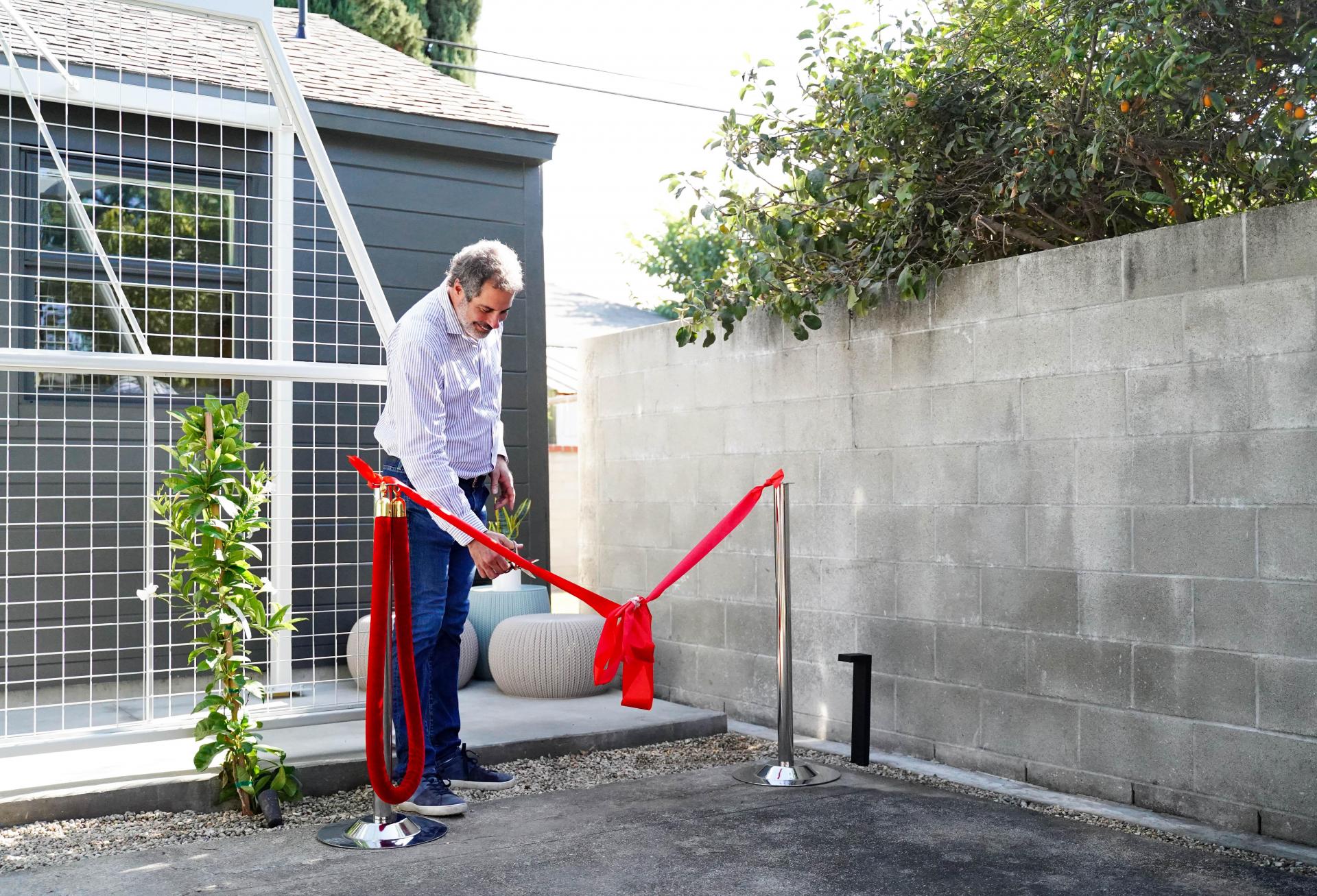 United Dwelling CEO Steven Dietz cuts the ceremonial ribbon at a resident's ADU in Los Angeles